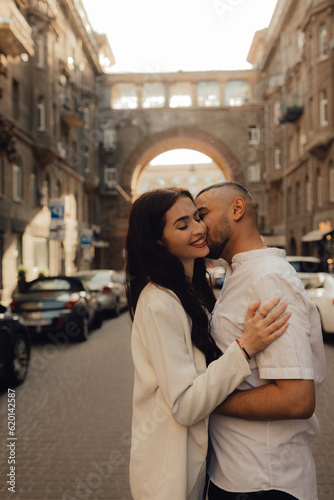 The couple walks around Kyiv. Old city. Love story. Walk around the city. A woman in a white suit. Guy in a t-shirt and jeans. Love and hugs. To cross the road. No focus blurred and noise effect