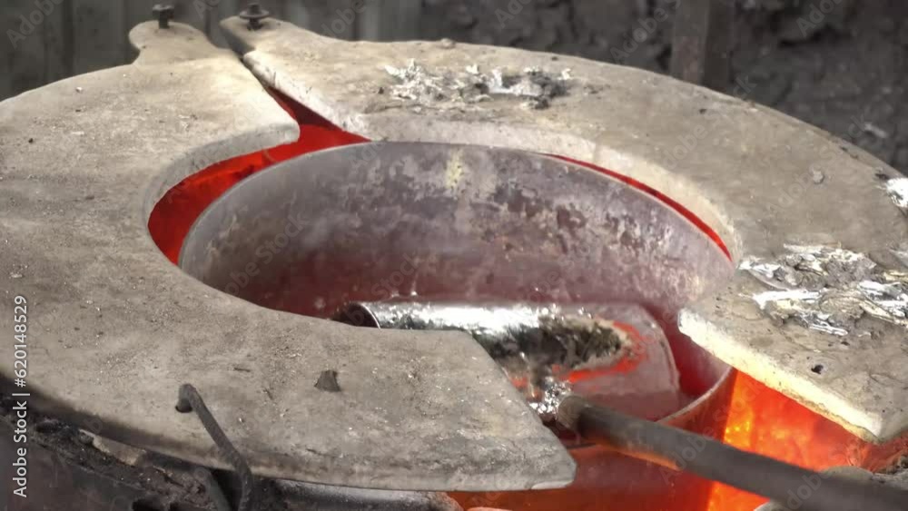 Workers in a foundry pouring liquid Aluminum to a sand cast Workers in a foundry pouring liquid Aluminum to a sand cast
