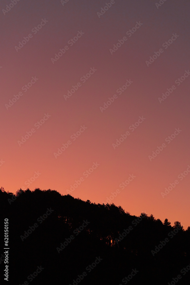 Dark silhouette of hills on pink sunrise view. Sundown landscape with purple color sky