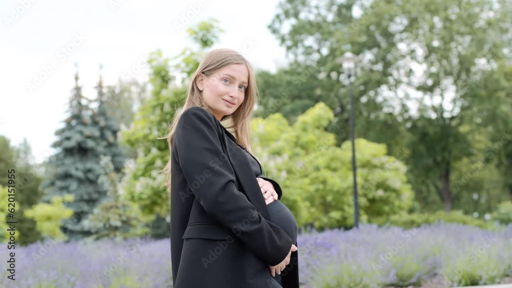 Young Caucasian pregnant woman rubbing her belly. Expecting female in park touching stomach on her third trimester Young Caucasian pregnant woman rubbing her belly. Expecting female in park touching stomach on her third trimester