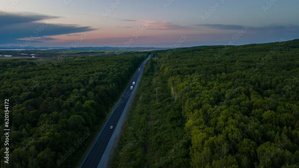 Aerial view of the Slope of a Mountain Range and tall taiga near to the river at summer cloud evening with horizon, blue