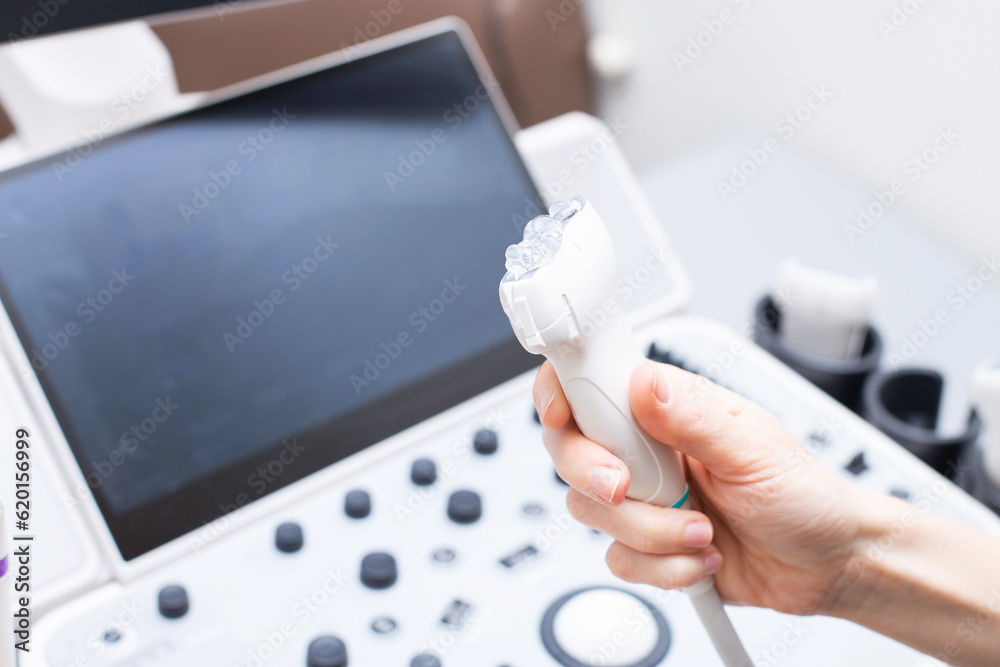 Woman doctor's hand aholding a medical gel to ultrasonic sensor of ultrasound machine in the clinic