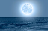 Night sky with blue moon over the calm blue sea 