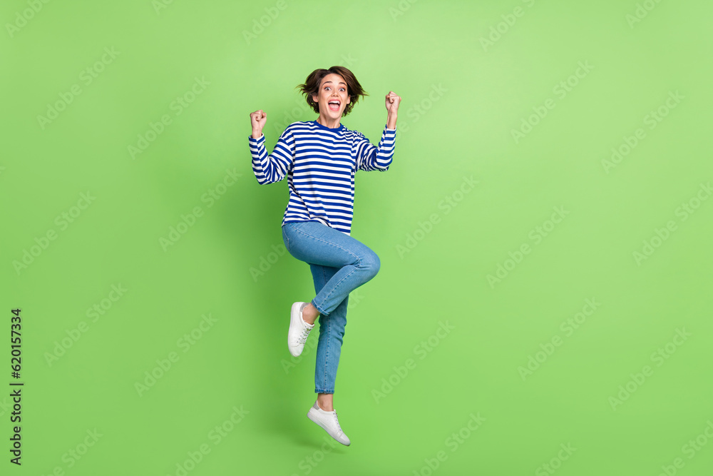 Full body cadre of young girl sailor shirt jump overjoyed fists up victory her team successful project isolated over green color background Full body cadre of young girl sailor shirt jump overjoyed fists up victory her team successful project isolated over green color background