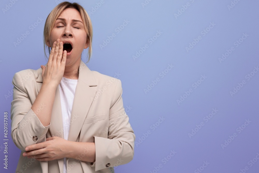 sleepy tired blond business young woman in jacket yawns on studio background sleepy tired blond business young woman in jacket yawns on studio background