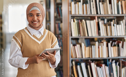 Valokuva Portrait of muslim student smiling at camera while using tablet pc in library