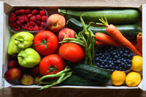 Wooden crate full of healthy seasonal fruit and vegetable. Top view, wooden background.