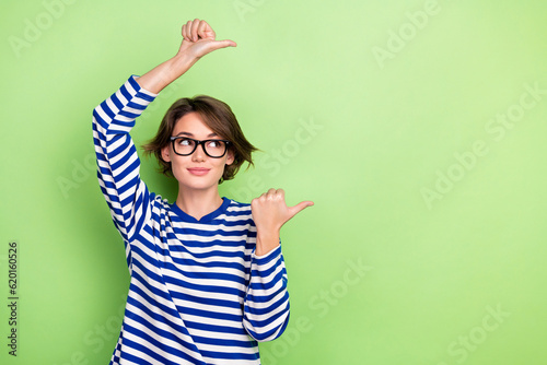 Photo of pretty business lady direct fingers empty space mockup wear spectacles striped shirt isolated green color background