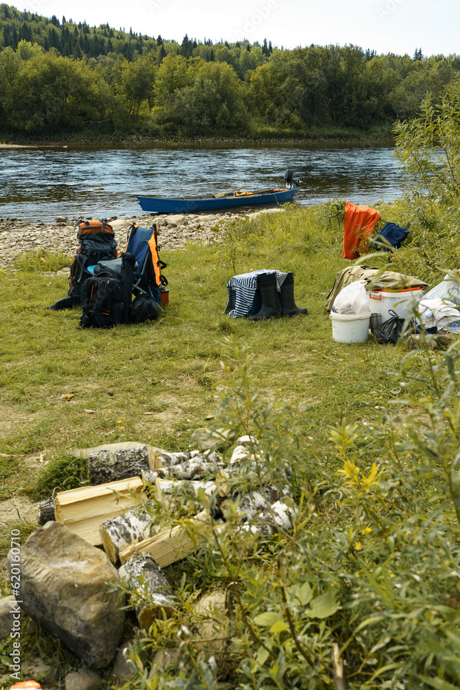 Fototapeta premium Camping equipment, backpacks, boots lie on the river bank. High quality photo