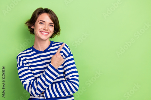 Photo of young beautiful lady manager pointing finger empty space news wear blue striped shirt isolated green color background © deagreez