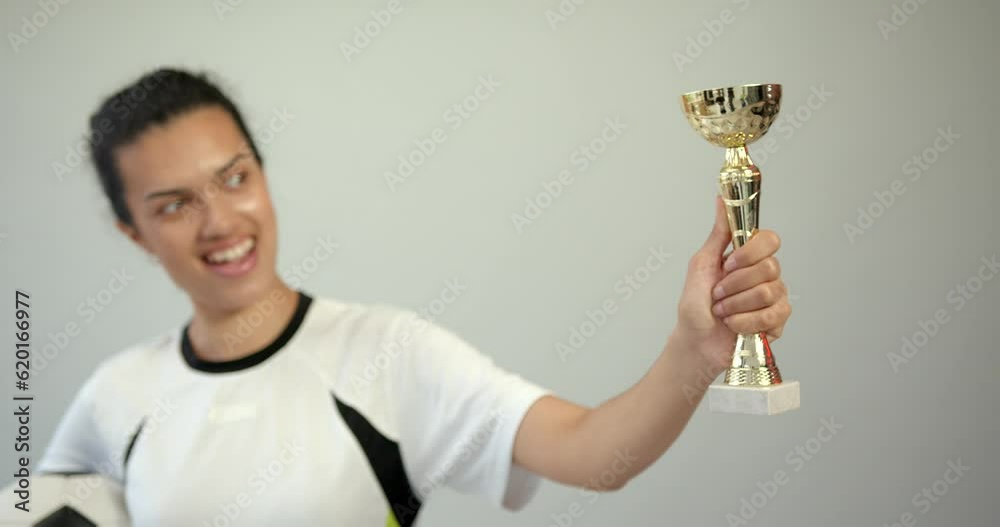 Female football player holding cup on background Female football player holding cup on background