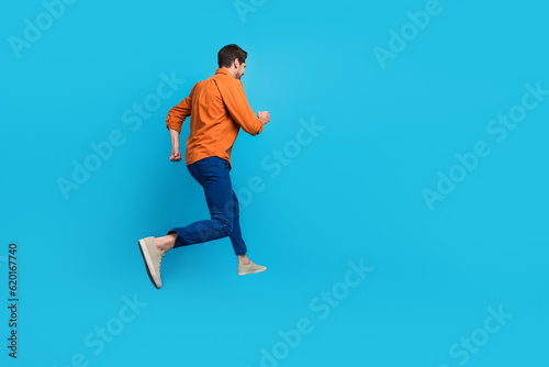 Full size profile rear portrait of energetic crazy young man jumping running empty space advert isolated on blue color background
