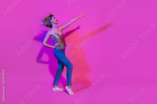 Profile full length photo of energetic lady dancing pointing finger empty space night club advert isolated neon vivid color background
