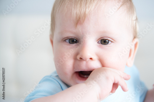 close up child with his fingers in his mouth  his teeth are teething. Baby teeth grow