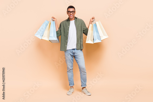 Full length photo of excited sweet man wear khaki shirt smiling rising bargains isolated beige color background