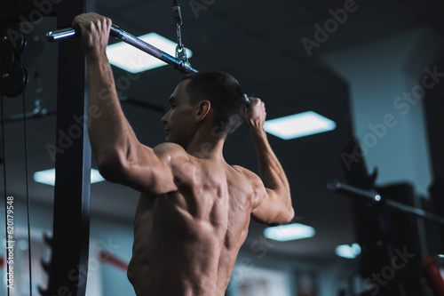 A man does a chest pulldown in the gym. photo