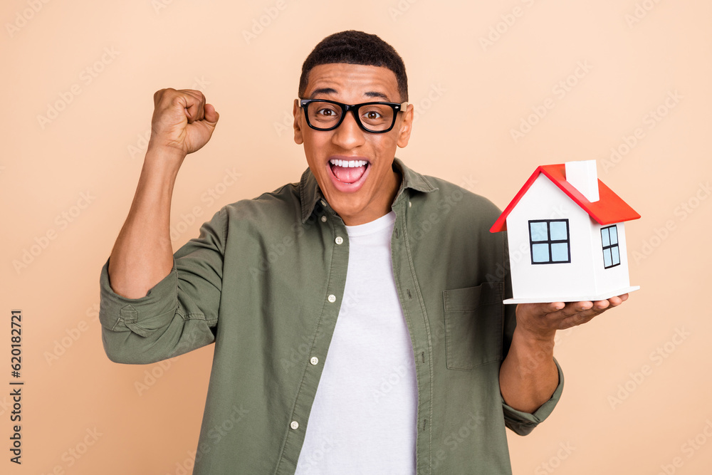 Photo of good mood ecstatic guy dressed khaki shirt glasses hold small house celebrate relocation isolated on pastel color background Photo of good mood ecstatic guy dressed khaki shirt glasses hold small house celebrate relocation isolated on pastel color background