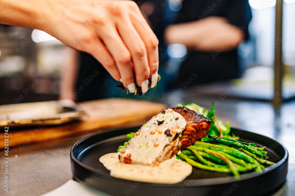 woman chef hand cooking salmon fish steak with asparagus and salad