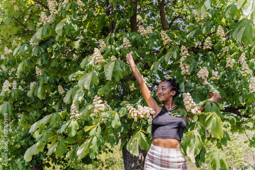 Spring, summer beauty portrait of african girl enjoy flowers under flowering chestnut tree.