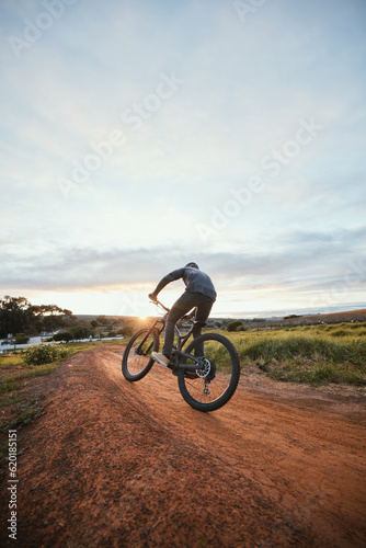 Sports, cycling and man on bicycle in countryside for training, workout and exercise in nature. Fitness, cyclist and person with mountain bike for adventure, freedom and ride on outdoor dirt road