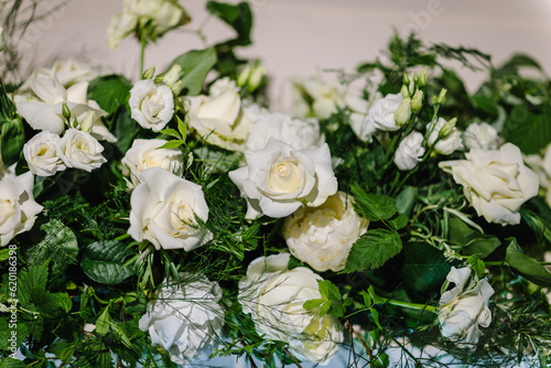 Festive table decorated with a composition of white flowers and greenery  and candles in the banquet hall. Table newlyweds covered with a tablecloth in the banquet area on a wedding party. Top view