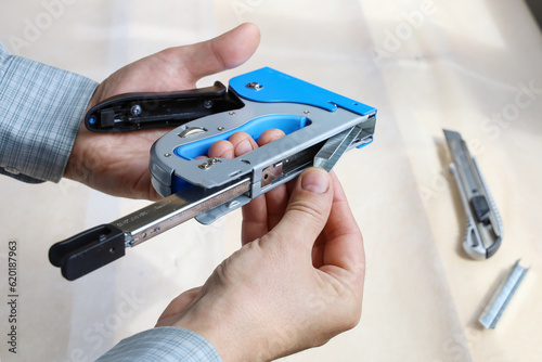 Hands filling construction stapler with new staples for job