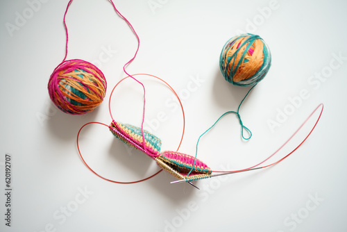 knitting with knitting needles by the magic loop method from multi-colored yarn on a white background