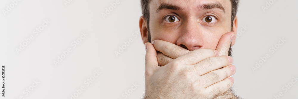 Bearded man with tattoo looking at camera while covering his mouth Bearded man with tattoo looking at camera while covering his mouth
