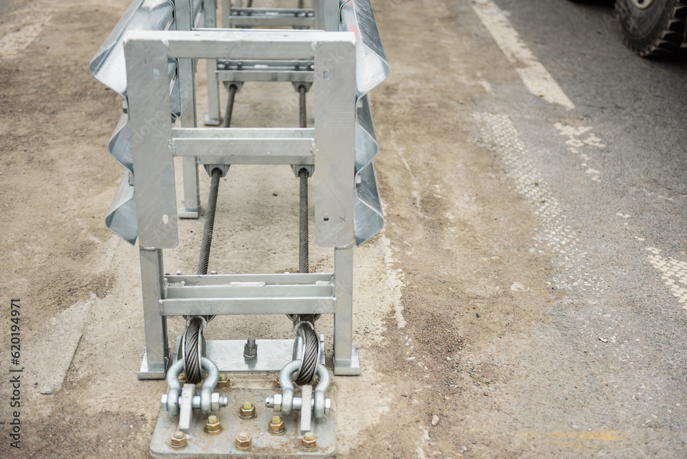 Installation of median crash barriers on highway. Metal road fencing of barrier type on freeway. Road guard rails. Safety barrier with a red and white striped sign. Protect vehicles from accidents.