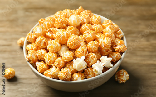 Bowl with tasty caramel popcorn on wooden table  MADE OF AI