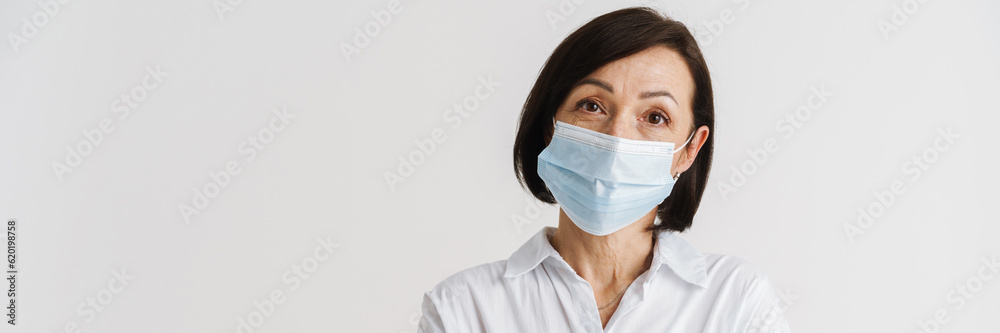 European mature woman in face mask posing with arms crossed