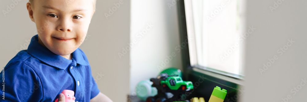 White boy with down syndrome playing with toys by window White boy with down syndrome playing with toys by window