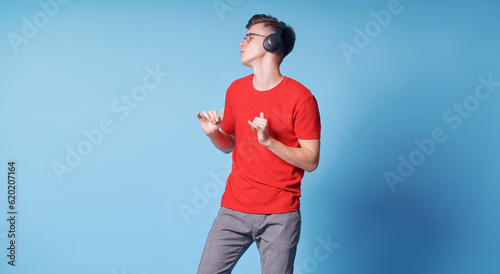 Enjoying the sound. Colorful portrait of happy young man with red t-shirt is listening music.