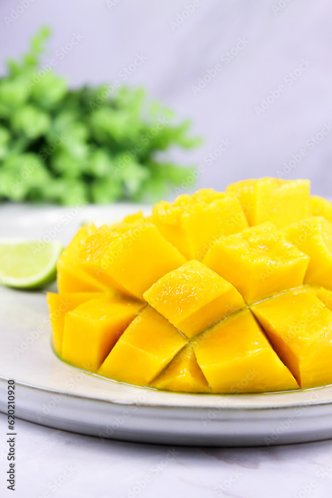 Mango sliced into cubes, close up. Yellow mango cut to cubes close-up with a lime slice, exotic indian ripe superfood. Raw food healthy eating concept. Sliced mango Mango sliced into cubes, close up. Yellow mango cut to cubes close-up with a lime slice, exotic indian ripe superfood. Raw food healthy eating concept. Sliced mango