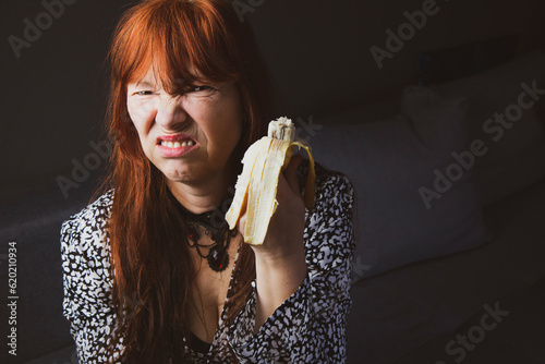 Frau ißt eine Banane und verzieht vor Ekel das Gesicht