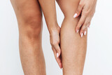 Irritation and redness on sensitive skin after epilation. Cropped shot of young tanned woman touching her leg with her hands after depilation on a white background. Hair removal with wax, epilator