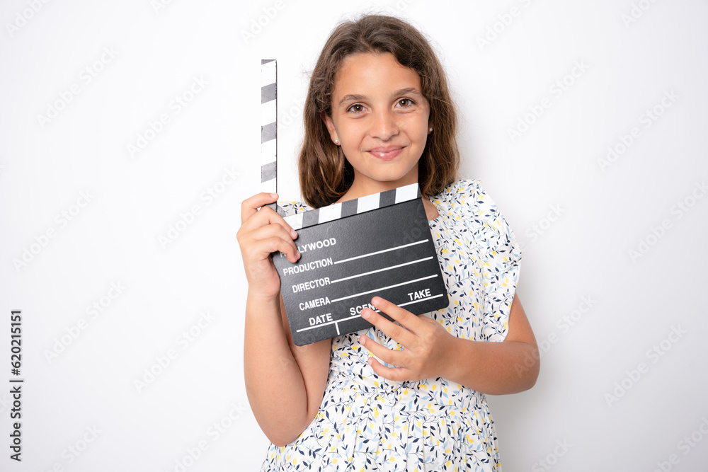Beautiful young girl, smiling to camera while holding a movie makers clapperboard. Isolated on studio white background. Beautiful young girl, smiling to camera while holding a movie makers clapperboard. Isolated on studio white background.