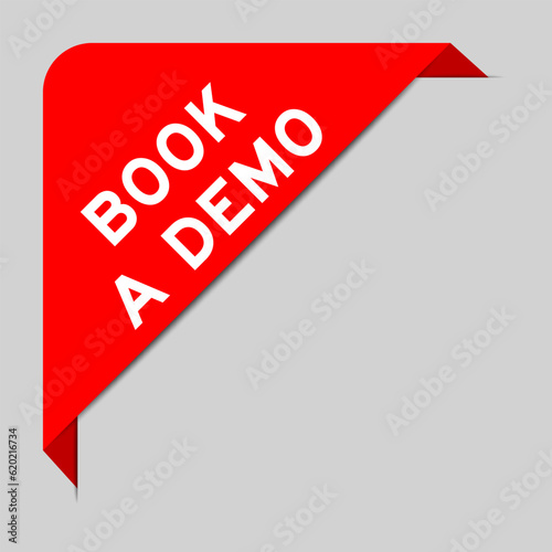 Red color of corner label banner with word book a demo on gray background