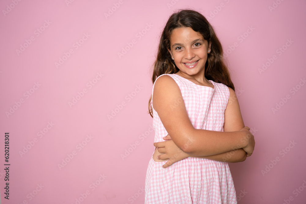 Photo of optimistic friendly schoolgirl dressed with pink dress hold arms folded isolated on pink color background