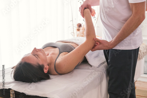Young Caucasian woman being treated by therapist to help alleviate pain or improve physical condition. Therapist doing pressure and massage exercises to improve patient's health. photo