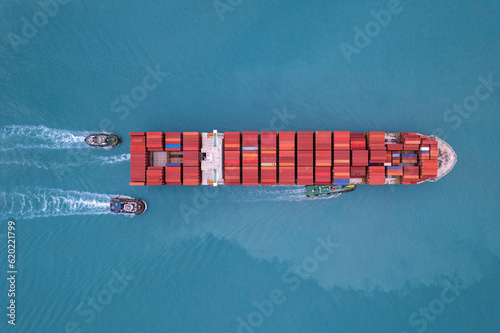 Top view Logistics and transportation of Container Cargo ship and Cargo plane with working crane bridge in shipyard at sunrise, logistic import export and transport industry tug boats