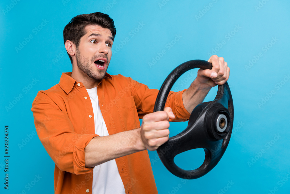 Photo of shocked impressed man dressed orange shirt driving auto empty space isolated blue color background Photo of shocked impressed man dressed orange shirt driving auto empty space isolated blue color background