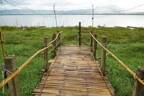 Wooden bamboo bridge with river and mountain scene.