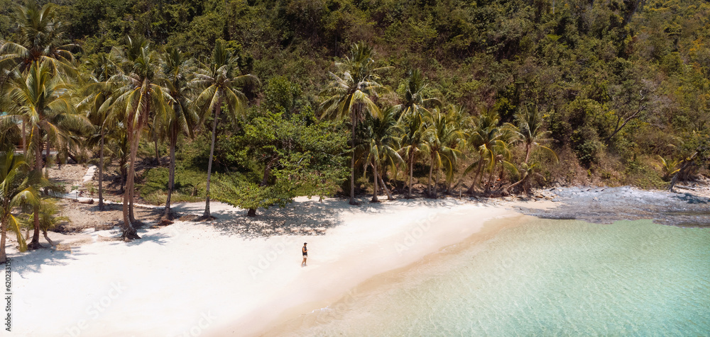 Piękna rajska plaża z białym piaskiem, palmami i turkusową wodą, osoba idąca po wybrzeżu. - obrazy, fototapety, plakaty 