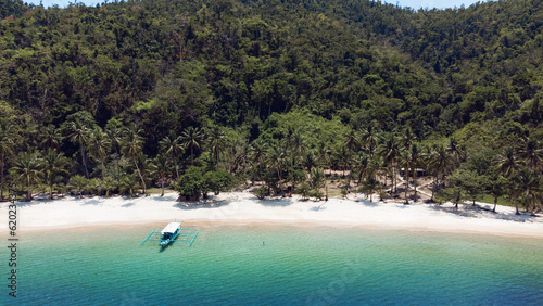 Łódź na tle turkusowej wody, piękna rajska wyspa, niesamowity letni krajobraz z plażą i palmami, ujęcie z drona.