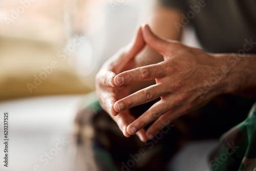 Hands clasped, soldier sitting and military person with anxiety, depression or problem on sofa. Army man, couch and ptsd, stress and crisis after war, trauma and waiting in living room alone in home