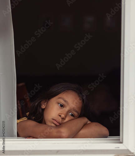 фотографія diverse child at home looking out window, lonely bored and sad