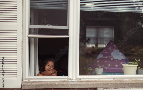 Принти на полотні diverse child at home looking out window, lonely bored and sad