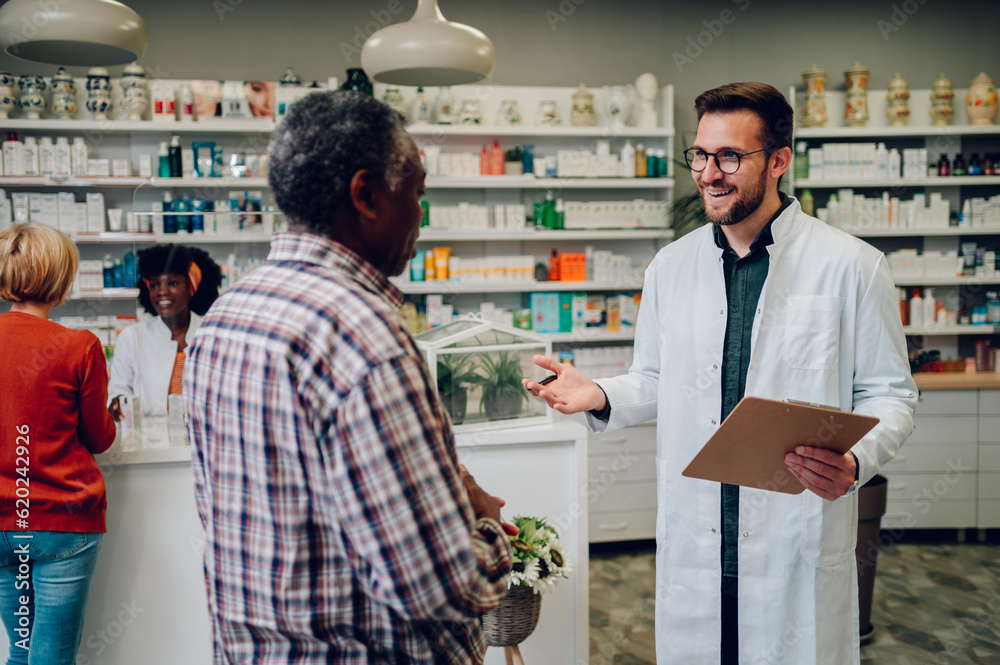 Portrait of a male pharmacist helping a senior black man patient in pharmacy
