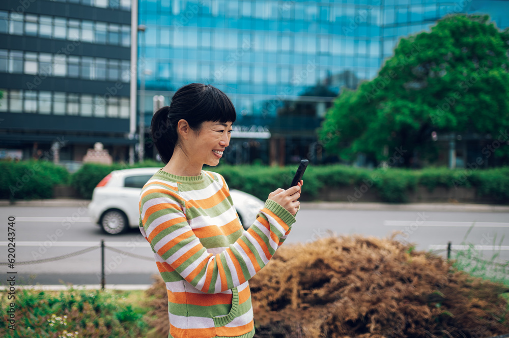 Smiling japanese woman having an online meeting outside on her mobile phone.
